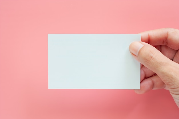 Hand, die leere Visitenkarten auf rosa Hintergrund hält