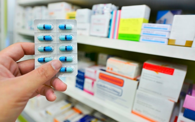 Hand, die Medizinkapselpackung an der Apotheke Drogerie hält