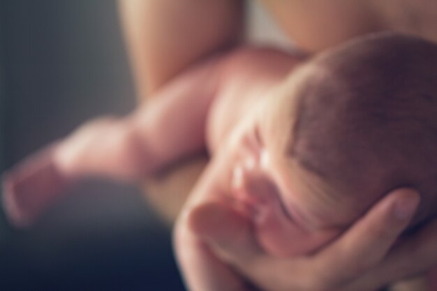 Foto hand, die neugeborenes baby mit weichem fokuseffekt weichem unschärfefoto hält