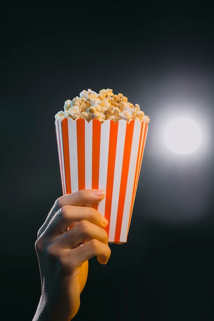 Hand, die Popcorn in gestreiftem Eimer hält, isoliert im Film