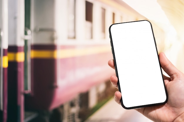 Hand, die Smartphone in der Bahnstation hält