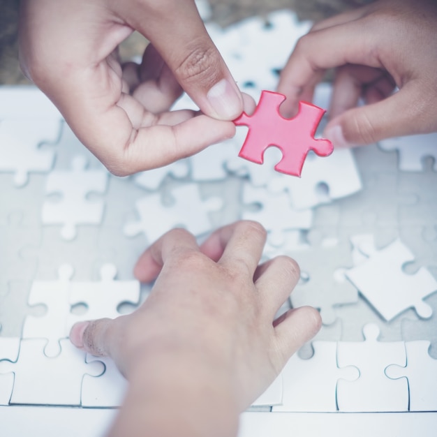 Hand, die Stück des leeren Puzzlespiels mit Papierrahmenhintergrund hält.