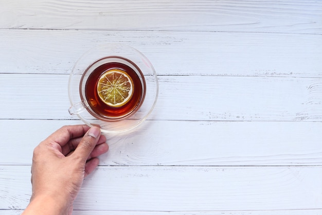 Hand, die Tasse Zitronentee mit Kopienraum hält.