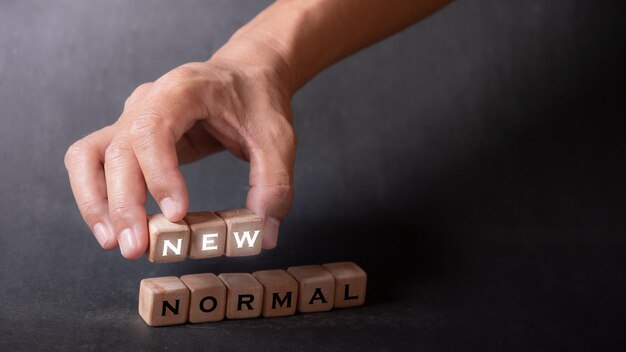 Foto hand, die würfel mit text zur veranschaulichung von neuen normal-wörtern hält