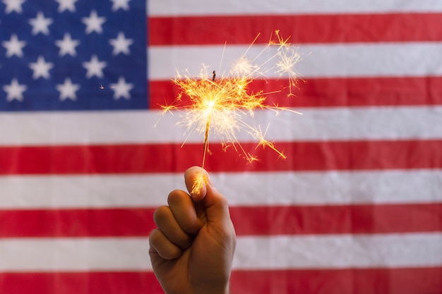 Foto hand, die wunderkerze vor usaflagge hält