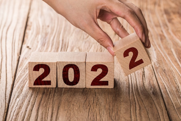 Hand dreht einen Block um, der 2021 bis 2022 ändert. Neujahr beginnt mit Feiertagen und Weihnachten