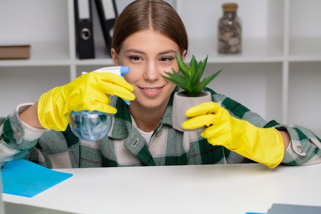 Hand einer Frau, die den Schreibtisch in gelben Handschuhen abwischt