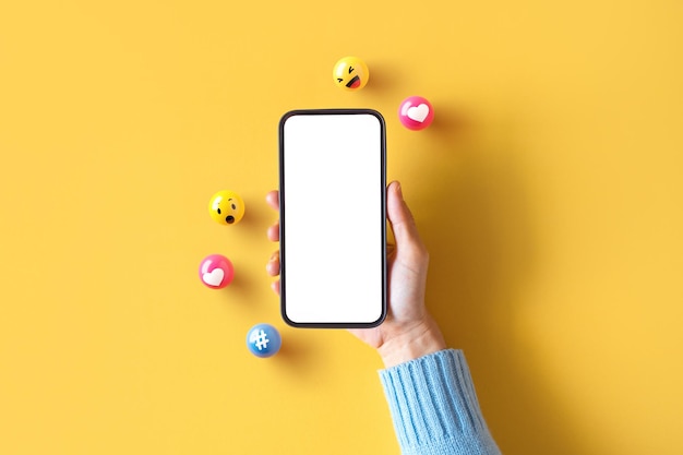 Hand einer frau, die ein leeres mobiltelefon mit symbol für soziale medien hält