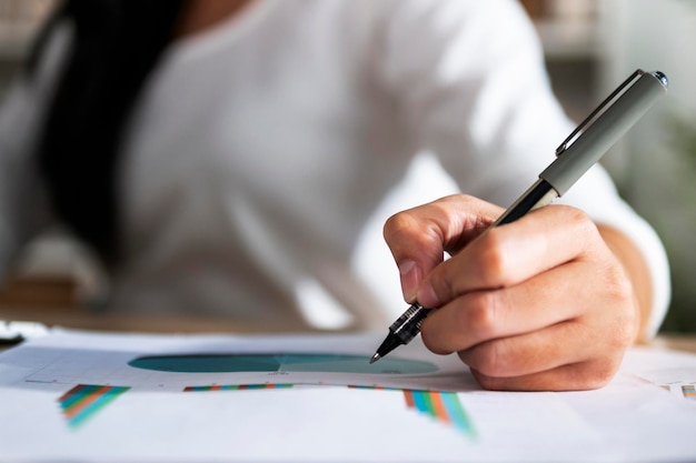 Hand einer Frau, die einen Stift hält und auf Papier schreibt, Bericht im Büro