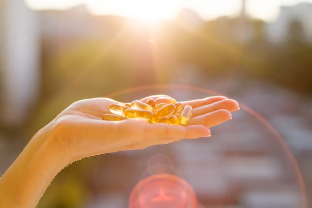 Hand einer Frau, die Fischöl Omega-3-Kapseln hält