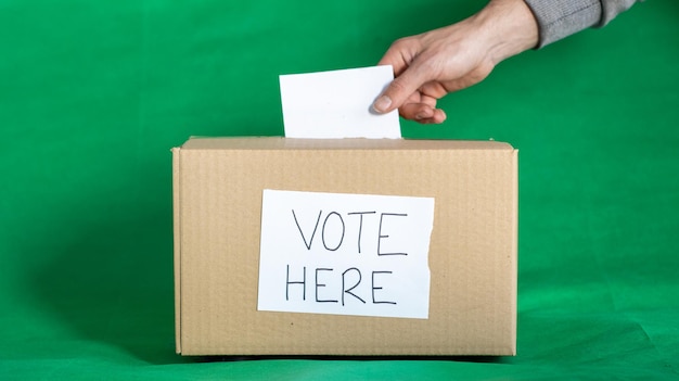 Hand einer Person, die während der Wahl Chroma-Hintergrund eine Stimme in die Wahlurne abgibt