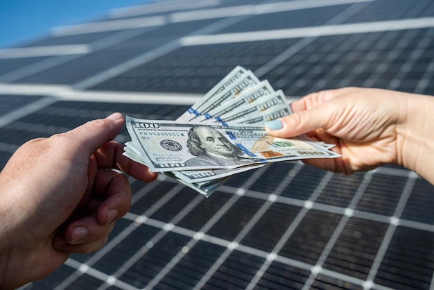 Hand eines jungen Mannes, der Dollar hält und sie überreicht, um neue Sonnenkollektoren zu installieren