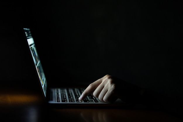 Hand eines Mannes, der Laptop-Computer in der Dunkelheit verwendet