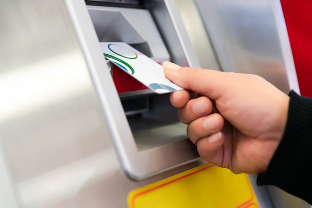 Hand eines Mannes mit einer Kreditkarte, unter Verwendung eines ATMs. Mann, der eine ATM-Maschine mit seiner Kreditkarte verwendet.