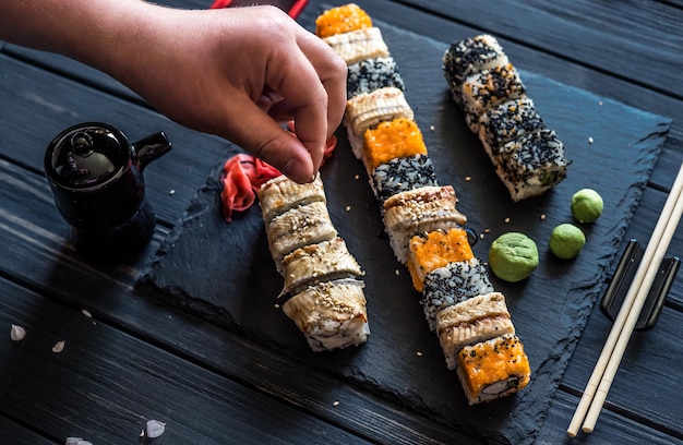 Hand eines Mannes mit Sesam über Sushi 2