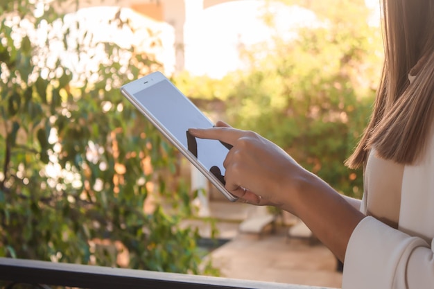 Hand eines unternehmungslustigen Mädchens mit einem Tablet auf einem Hotelbalkon