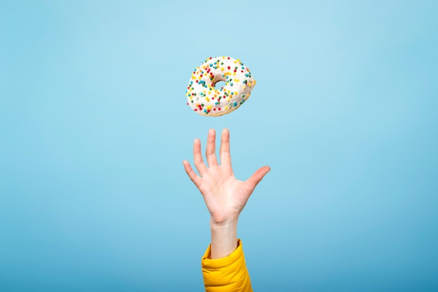 Hand fangen Sie einen Donut mit Zuckerguss. Konzept des Backens, handgemacht. Flache Lage, Draufsicht