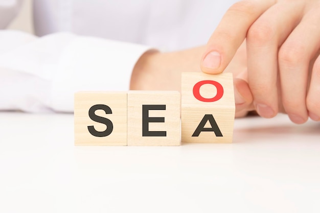 Hand flip SEO para blocos de cubo de madeira de texto SEA no fundo da mesa otimização de mecanismos de busca publicidade ideia estratégia conceito de marketing
