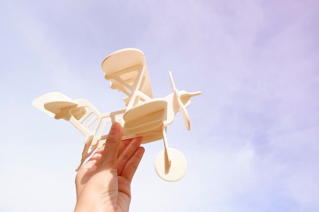 Foto hand frau mit spielzeug flugzeug gegen himmel. hintergrund, bild ist retro gefiltert