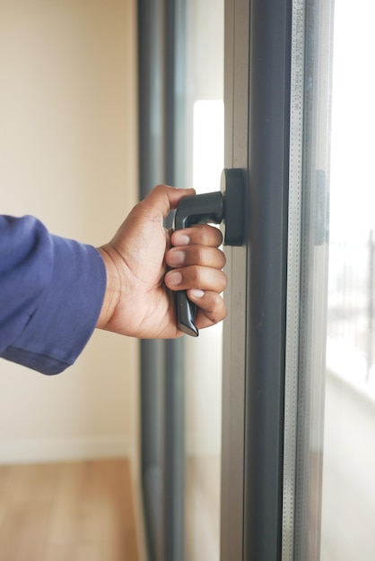 Hand geöffnetes graues Plastik-PVC-Fenster zu Hause am frühen Morgen