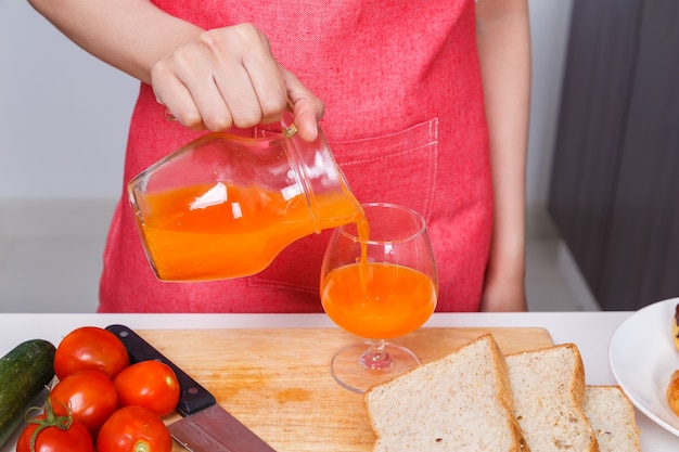 Hand gießt einen frischen Orangensaft in ein Glas