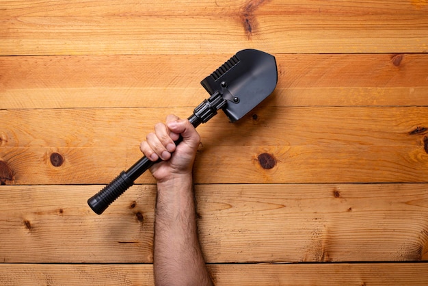 Hand greifen Schaufel auf hellem Holzhintergrund Tag der Arbeit