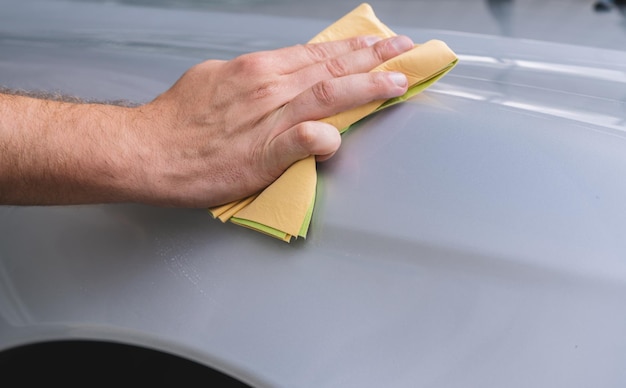 hand hält die mikrofaser in der hand und poliert das auto