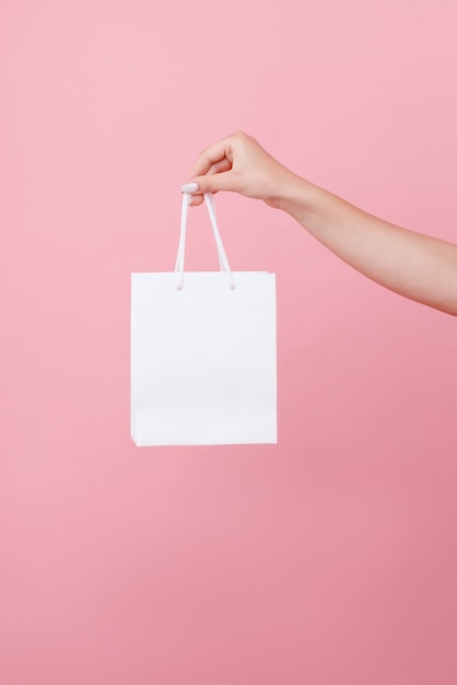 Hand hält die Tasche unter dem Logo auf einem rosa isolierten Raum