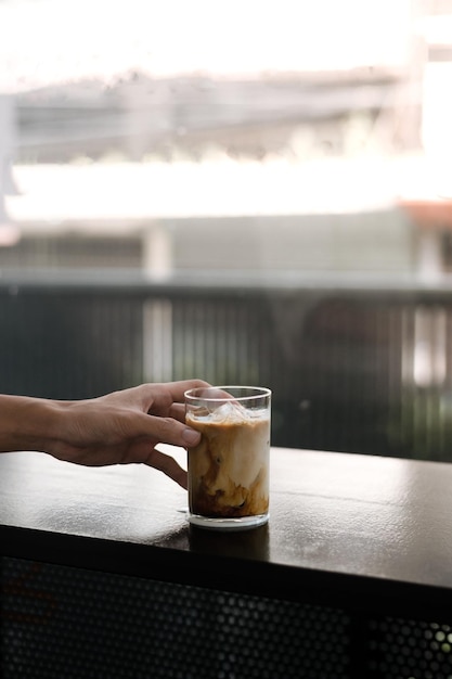 Hand hält ein Glas Eiskaffee