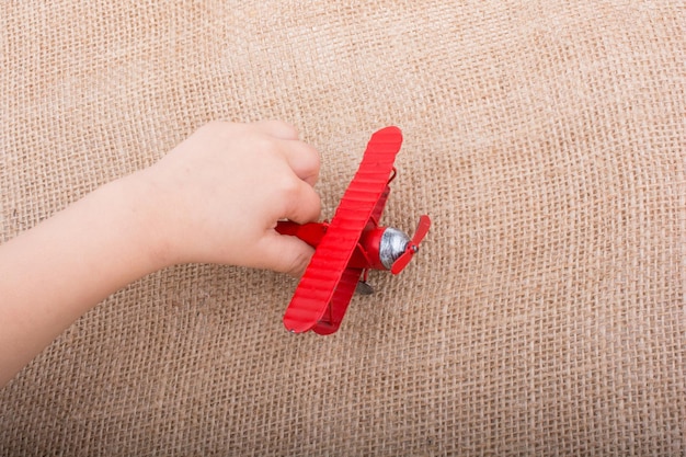 Hand hält ein Spielzeugflugzeug auf Leinenleinwand