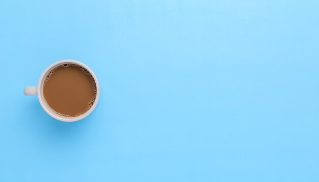 Hand hält eine Kaffeetasse auf blauem Hintergrund