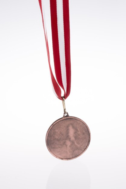 Hand hält eine Medaille mit rot-weißem Band