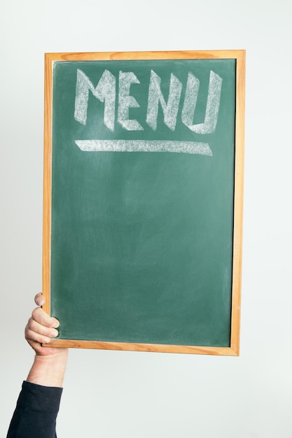 Hand hält eine Tafel mit dem Wort MENÜ handschriftlich in Kreide