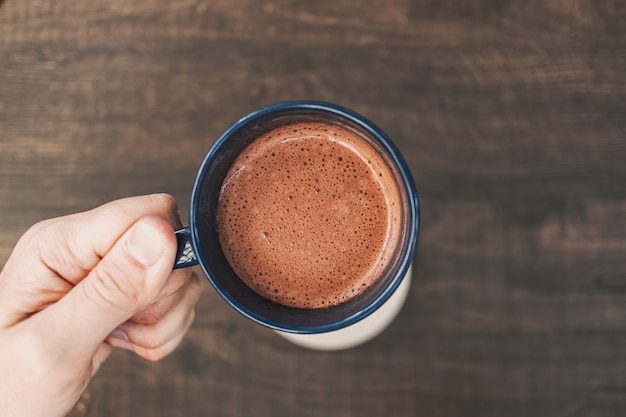 Hand hält eine Tasse heißen Kakao in einem Café