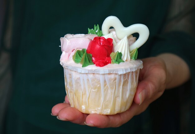 Hand hält einen Cupcake mit schönen Rosen verziert