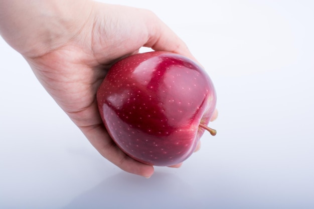 Hand hält einen schönen roten Apfel auf weißem Hintergrund