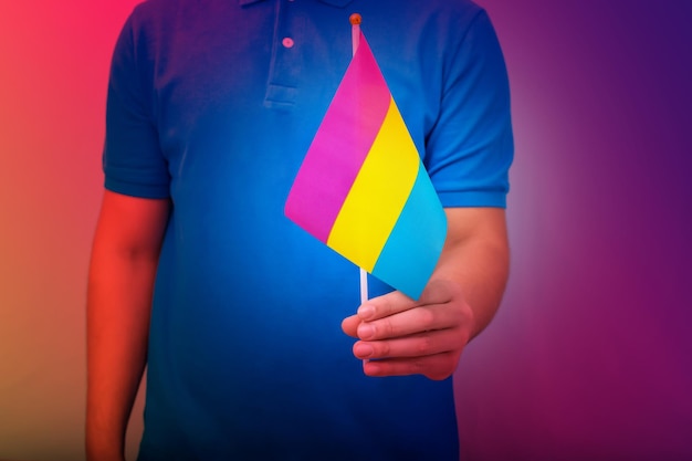 Hand hält Flagge in den Farben des pansexuellen Stolzes