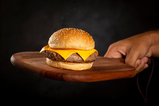 Hand hält Hamburger auf dunklem Hintergrund