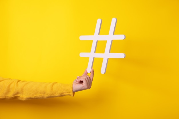 Hand hält Hashtag-Symbol, macht wichtiges Thema populär, setzt Trends im Internet.