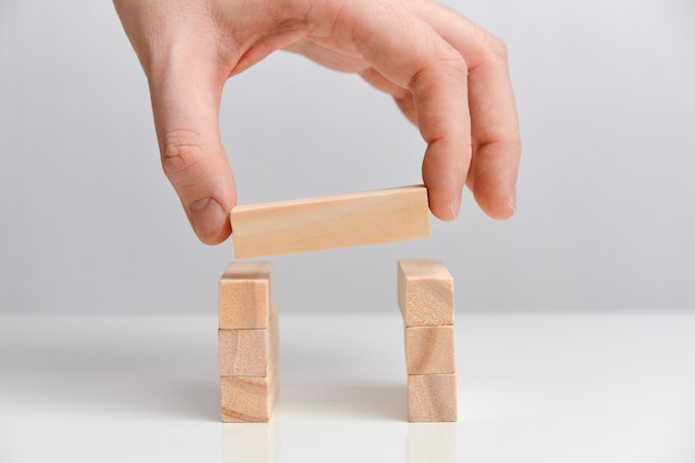 Hand hält Holzblock auf zwei Holzblöcken