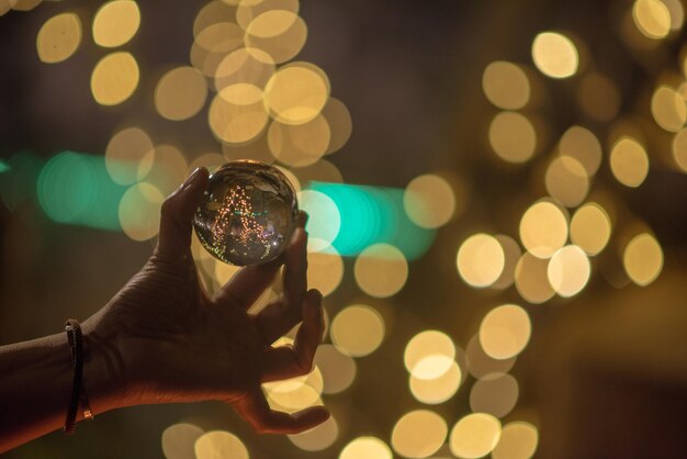 Hand hält Kristallkugel gegen defokussierte Lichter