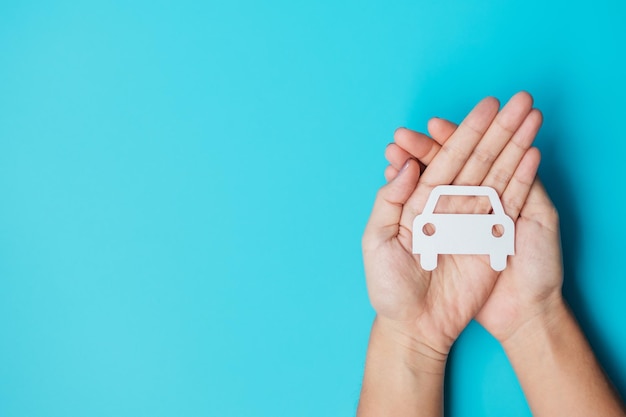 Hand hält Papier Autoausschnitt auf blauem Hintergrund Fahrzeugversicherungsgarantie Autovermietung Transport Wartungs- und Reparaturkonzept