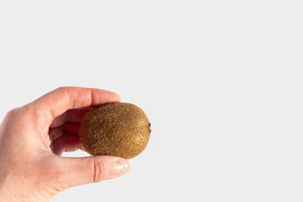 Hand hält reifen ungeschälten Kiwis auf weißem Hintergrund Kopie Raum Kiwi ist ein natürliches diätetisches Produkt eine Quelle von Vitaminen und Antioxidantien Gesundes vegetarisches Ernährungskonzept