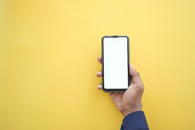 Hand hält Smartphone mit weißem Bildschirm auf gelbem Hintergrund