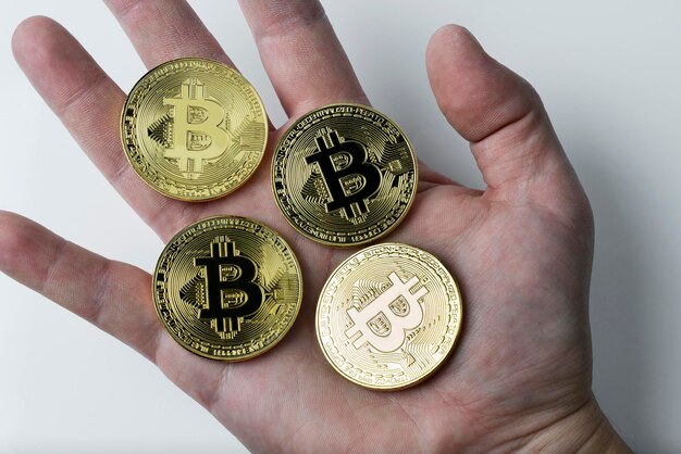 Hand hält vier Bitcoin auf weißem Hintergrund