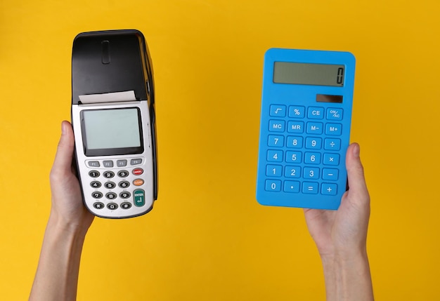 Hand hält Zahlungsterminal und Taschenrechner auf gelbem Hintergrund Zahlung für Einkäufe