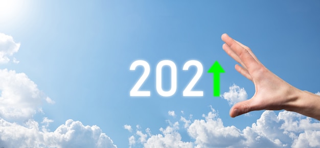 Hand halten 2021 positives Symbol auf Himmelhintergrund. Plangeschäft positives Wachstum im Jahr 2021 Konzept. Geschäftsmann planen und erhöhen positive Indikatoren in seinem Geschäft, Aufwachsen von Geschäftskonzepten.