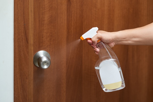 Hand halten Flasche Alkohol sprühen Desinfektionstür.