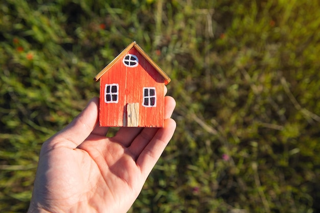 Hand halten Hausmodell auf grünem Gras Hintergrund Öko-Haus-Konzept