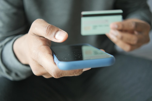 Hand halten Kreditkarte und Smartphone online einkaufen